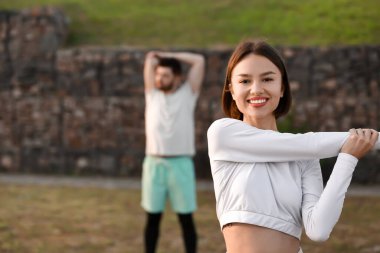 Erkek arkadaşıyla dışarıda esneme hareketleri yapan genç bir kadın.