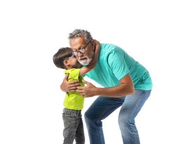 Küçük çocuk beyaz arka planda büyükbabasına sarılıyor.
