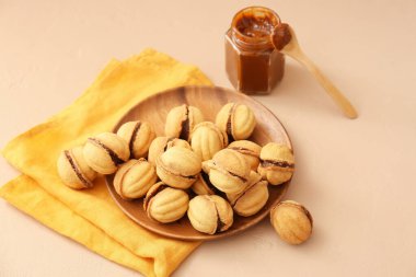 Lezzetli ceviz şekilli kurabiyeler ve bej arka planda kaynamış konsantre süt tabağı.