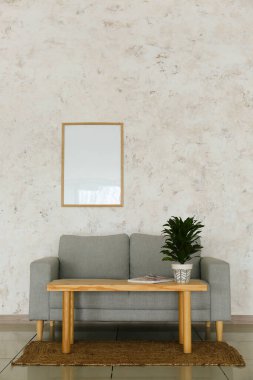 Modern oturma odasının içinde şık bir kanepe, masa ve çiçek var.