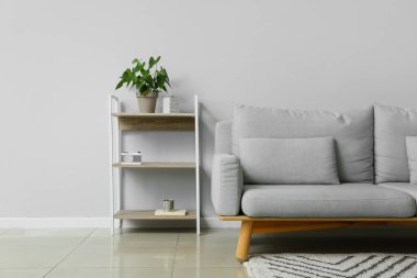 Modern oturma odasının içinde şık bir kanepe ve raf ünitesi var.