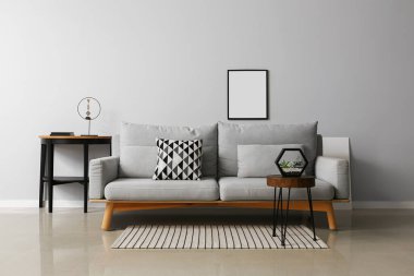 Modern oturma odasının içinde şık bir kanepe, masa ve fotoğraf çerçevesi.