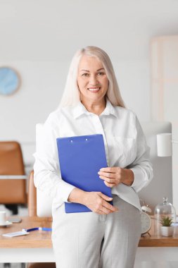 Ofisteki iş yerinin yanında olgun bir sekreter.