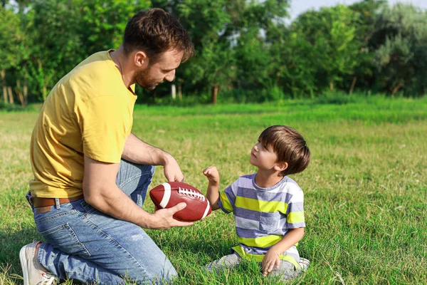 父亲教他的小儿子如何在战场上打橄榄球 — 图库照片