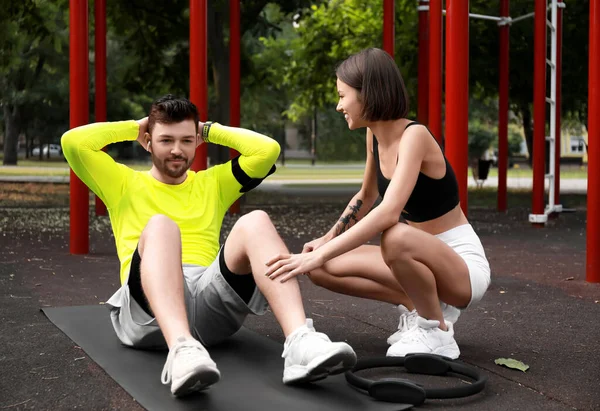 在运动场上和妻子一起做腹肌运动的年轻人 — 图库照片