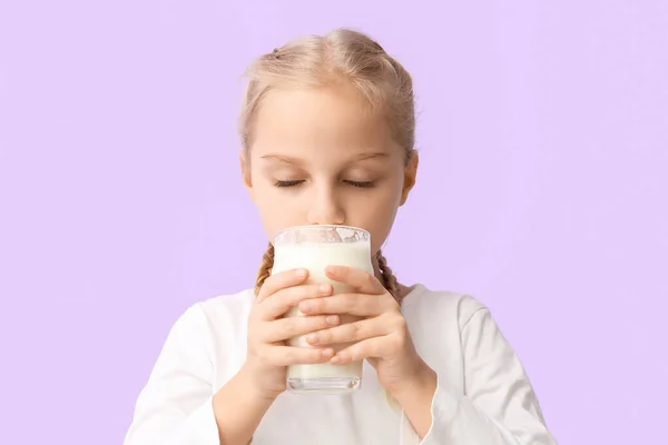 Милая Маленькая Девочка Пьет Молоко Сиреневом Фоне — стоковое фото