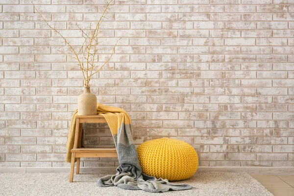 Modern pouf and step ladder near light brick wall in room