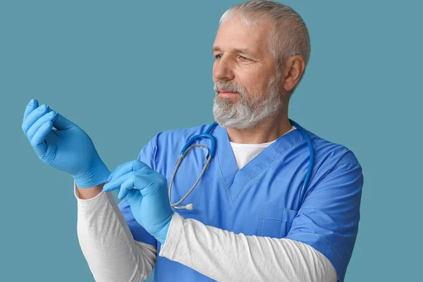 Ältere Männliche Arzt Mit Handschuhen Auf Blauem Hintergrund — Stockfoto