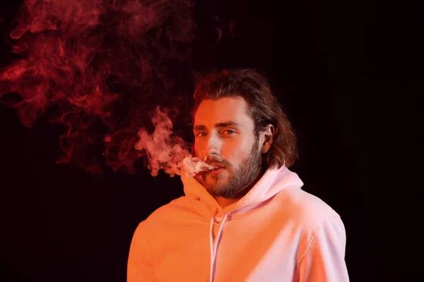 Smoking young man on black background