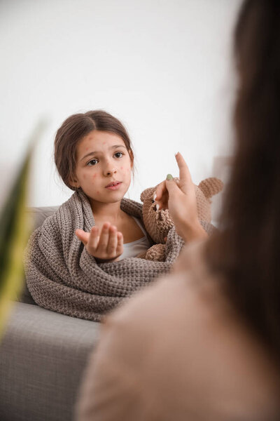 Mother applying remedy on skin of her little daughter ill with chickenpox at home