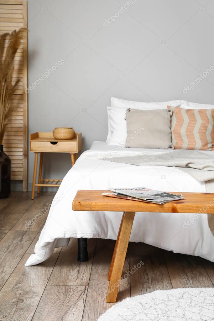 Bed with wooden bench in interior of modern bedroom
