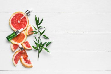 Beyaz ahşap arka planda greyfurt yağı şişeleri