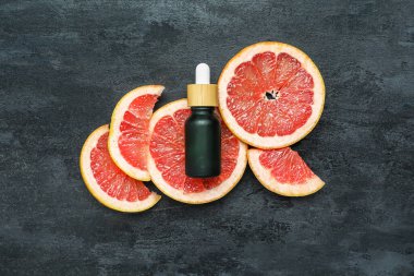 Koyu arkaplanda bir şişe greyfurt yağı