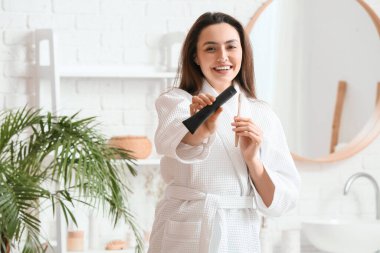 Aktif hale getirilmiş kömür diş macunu ve fırçasıyla banyoda güzel bir genç kadın.