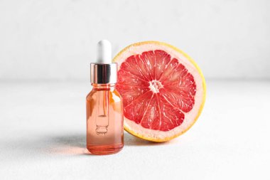 Temel yağlı bir şişe ve hafif arka planda yarım greyfurt.