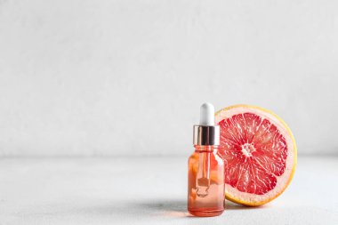 Temel yağlı bir şişe ve hafif arka planda yarım greyfurt.