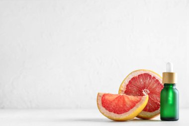Bir şişe gerekli yağ ve arka planda sulu greyfurt.