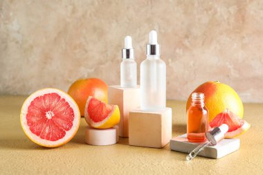 Renkli arka planda gerekli yağ şişeleri ve olgun greyfurtlarla kompozisyon