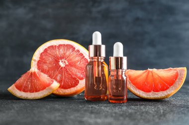 Esaslı yağlı şişeler ve koyu arkaplanda olgun greyfurt.