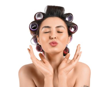 Beyaz arka planda saç bigudileri olan güzel bir kadın.