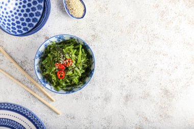 Sağlıklı deniz yosunu salatası, susam ve hafif arkaplanda kırmızı biber.