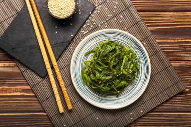 Sağlıklı deniz yosunu salatası ve ahşap arka planda susam.