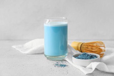 Bir bardak mavi kibrit çayı, arkaplanda barut ve kase.