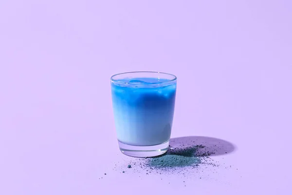 紫色背景的蓝色马沙茶和粉末玻璃 — 图库照片
