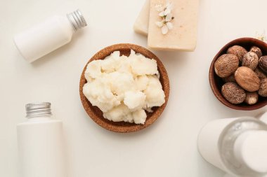 Hafif arka planda bir kase Shea yağı, fındık ve kozmetik