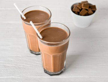 Beyaz ahşap arka planda lezzetli çikolatalı süt bardakları