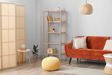 Rahat pouf, kanepe ve raf ünitesi ışık duvarının yanında.