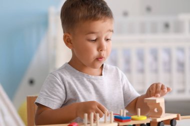 Odada tahta oyuncaklarla oynayan sevimli küçük çocuk.
