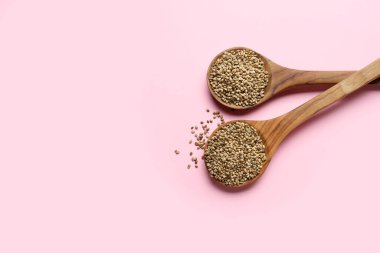 Renkli arkaplanda kenevir tohumları olan kaşıklar