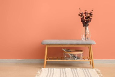 Vazoda okaliptüs, sepet ve şarjör ile pembe duvarın yanında yumuşak bank.