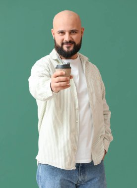 Yeşil arka planda bir fincan kahvesi olan kel adam.