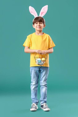 Tavşan kulaklı ve sepetinde Paskalya yumurtaları olan sevimli küçük bir çocuk.