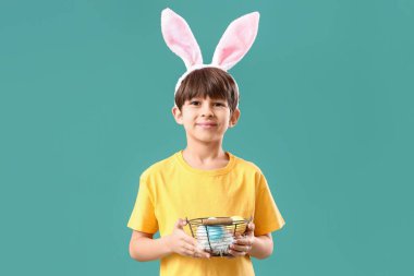 Tavşan kulaklı ve sepetinde Paskalya yumurtaları olan sevimli küçük bir çocuk.