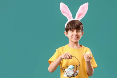 Tavşan kulaklı ve sepetinde Paskalya yumurtaları olan sevimli küçük bir çocuk.