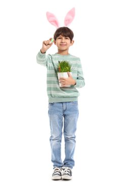 Tavşan kulaklı şirin bir çocuk elinde paskalya yumurtalarıyla beyaz arka planda çiçek tutuyor.