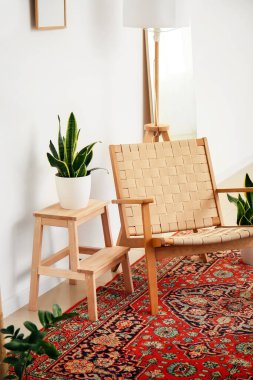 Eski halısı, koltuğu ve çiçekleri olan rahat bir oturma odası.