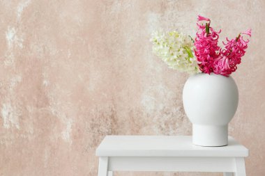 Vazo ve sümbül çiçekleri renkli duvarın yanındaki merdiven taburesinde.