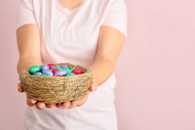 Arkaplanda çikolata yumurtalı yuva tutan kadın.