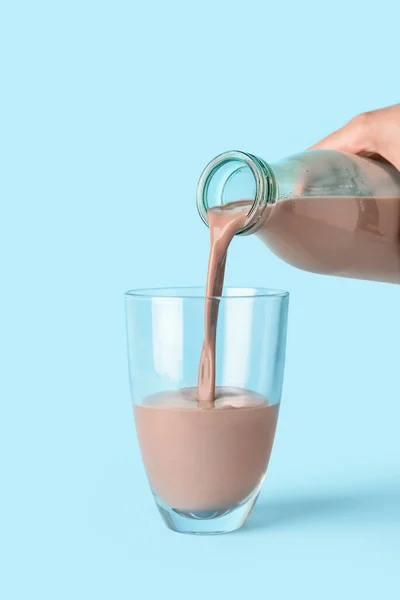 Gießen Von Köstlicher Schokoladenmilch Aus Der Flasche Glas Auf Farbigem — Stockfoto