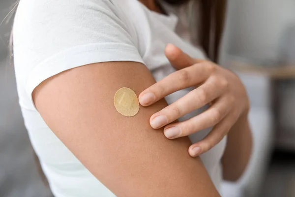 Young woman with applied nicotine patch at home, closeup. Smoking cessation