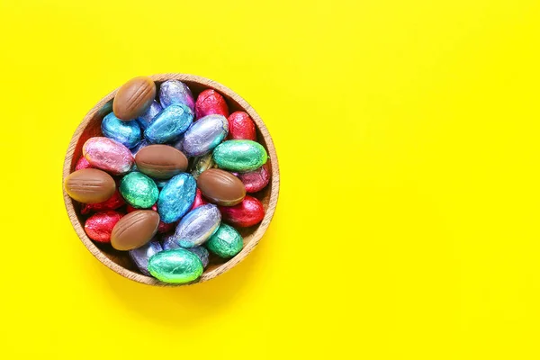 黄色の背景においしいチョコレートの卵とボウル — ストック写真