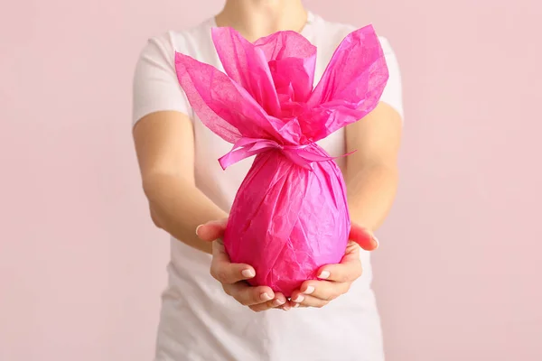 Mujer Sosteniendo Huevo Pascua Chocolate Envuelto Papel Rosa Sobre Fondo — Foto de Stock