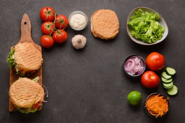 Koyu arkaplanda çörekler ve malzemelerle taze kebap.