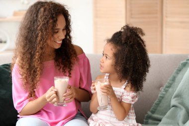 Küçük Afro-Amerikalı kız ve annesi evde kakao bardaklarıyla
