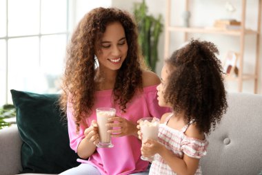 Küçük Afro-Amerikalı kız ve annesi evde kakao bardaklarıyla