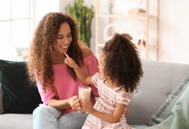 Küçük Afro-Amerikalı kız ve annesi evde bir bardak kakao ile